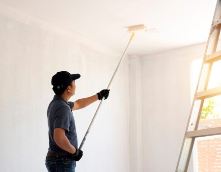 Asian rear view of a male painter drawing a wall with paint roll v